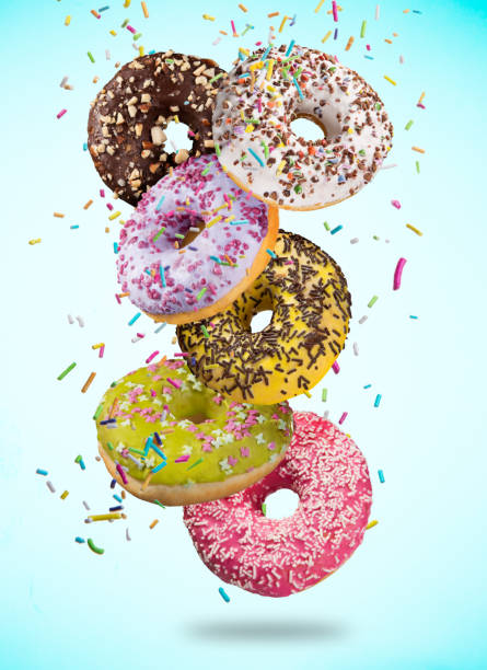 istock Tasty doughnuts in motion falling on pastel blue background 958693198