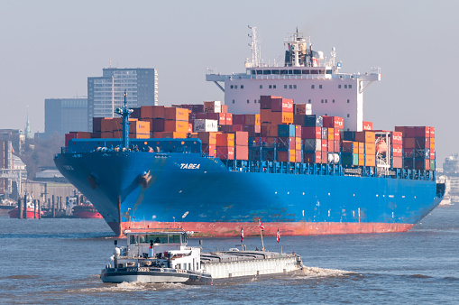 Hamburg, Germany - April 07, 2014: Container vessel Tabea is leaving the port of Hamburg, freight barge in foreground.
