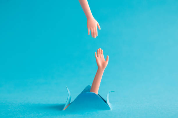 Two plastic hands on pastel blue background support abstract concept. Helping hand to drowning person minimal creative concept. doll stock pictures, royalty-free photos & images