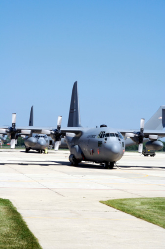 Three United States Air Force C-130 Hercules transport planes sit on a tarmac. 