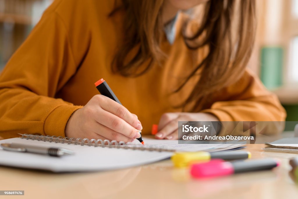 Young unrecognisable female college student in class, taking notes and using highlighter. Focused student in classroom. Authentic Education concept. Studying Stock Photo