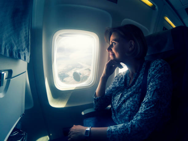 istock Woman looking through window in airplane 958698090
