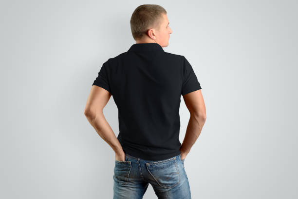 istock Back Mockup  black cotton  polo shirt on a man posing on a gray background. 958698734