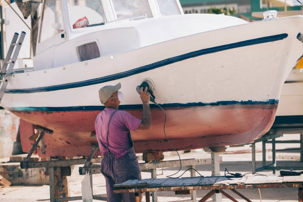 um homem prepara-se um barco de coloração. - industrial ship shipping painting repairing - fotografias e filmes do acervo