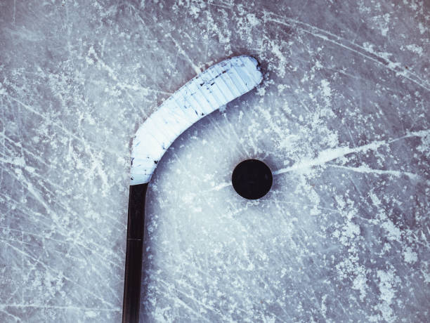 istock hockey puck and stick on the ice texture background 958701308