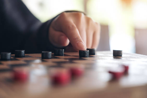 istock Closeup image of people playing and moving checkers in a chessboard 958703874