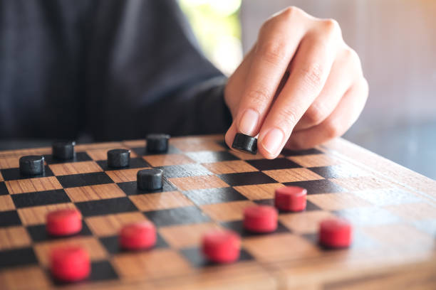 istock Closeup image of people playing and moving checkers in a chessboard 958703980