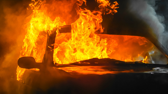 Crashed car burning at night.