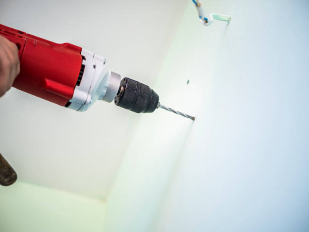 istock young casual man doing works at home with drill 958709332