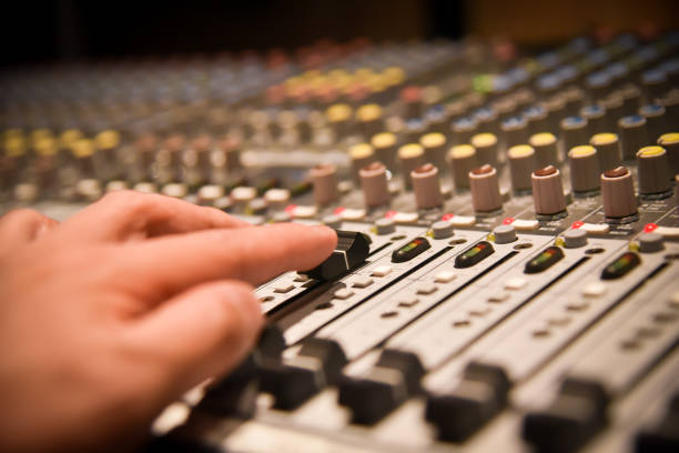 istock close-up hands of sound engineer adjusting audio mixer controller for live music and studio equipment. This is a quality audio system for professionals. vintage tone & effect light in control room. 958710444