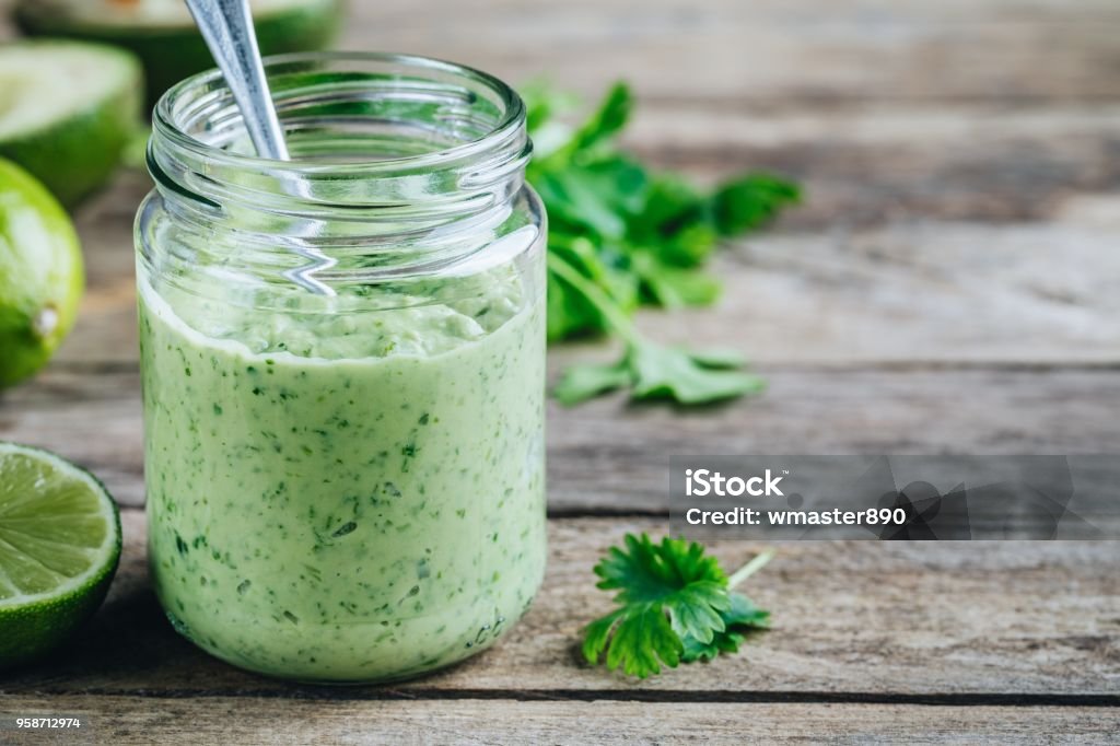 green salad dressing with avocado, lime and cilantro in a glass jar green salad dressing with avocado, lime and cilantro in a glass jar on a rustic background Salad Dressing Stock Photo