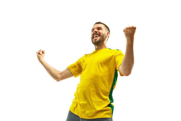 Brazilian fan celebrating on white background Brazilian fan celebrating on white background. The young man in soccer football uniform as winner isolated at white studio. Fan, support concept. Human emotions concept. brazilian culture stock pictures, royalty-free photos & images