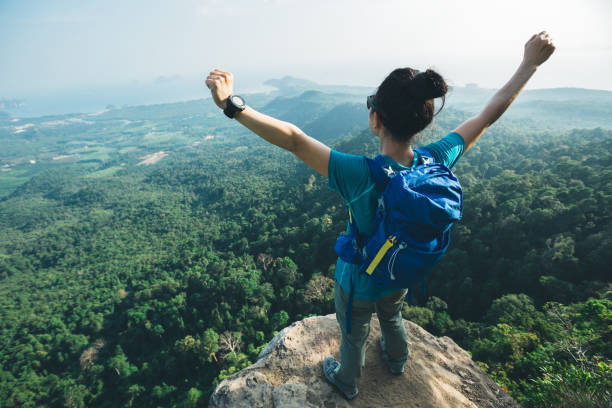 istock successful woman hiker cheering on mountain peak cliff edge 958716932