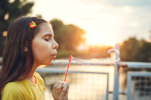 istock Cute little girl blowing soap bubbles 958718058