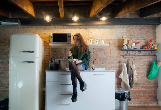 istock Beautiful girl eating salad in a modern kitchen 958720168