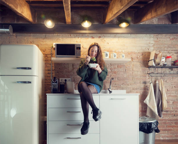 istock Beautiful girl eating salad in a modern kitchen 958720170