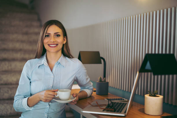 istock Relaxed young businesswoman having coffee while working on laptop 958727570