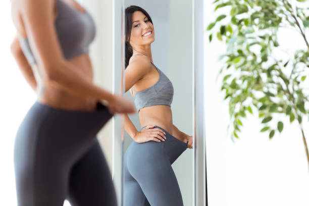 Beautiful young woman looking herself reflection in mirror at home.