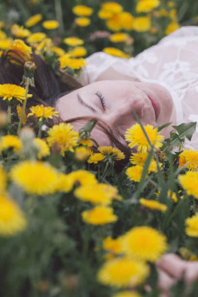 istock Young woman lying in dandelion 958730374