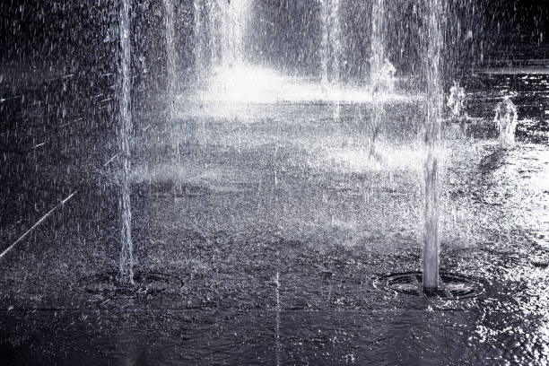 istock Water jets of a modern fountain on a stone pavement - toned image 958735294
