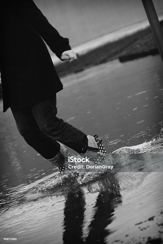 splashy girl splashing in a puddle, shot in black and white, grain added Autumn Stock Photo