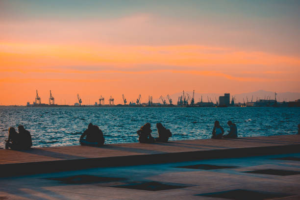 istock People sitting on a quay enjoying a sunset 958739138