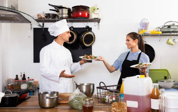 istock Man cook giving to waitress ready to serve salad 958742948
