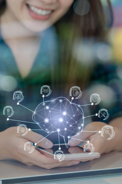 Polygonal brain shape of an artificial intelligence with various icon of smart city Internet of Things Technology over Asian businesswoman hand using the smart mobile phone,AI and business IOT concept stock photo