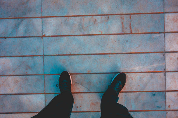 istock man looking down to his sport shoes on marble ground 958743512