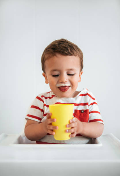 portrait of boy drinking milk on an open cup - milk mustache imagens e fotografias de stock