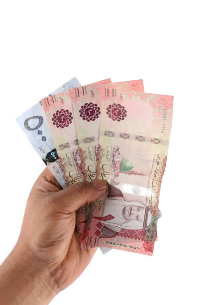 istock Saudi man counting thousands Saudi Riyal isolated on white background 958751842