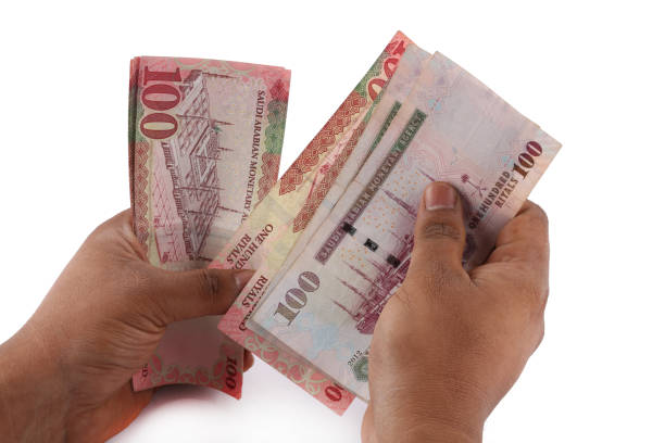 istock Saudi man counting thousands Saudi Riyal isolated on white background 958752598