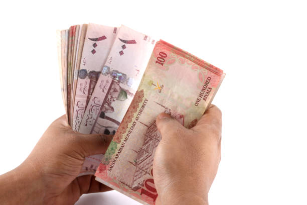istock Saudi man counting thousands Saudi Riyal isolated on white background 958753070