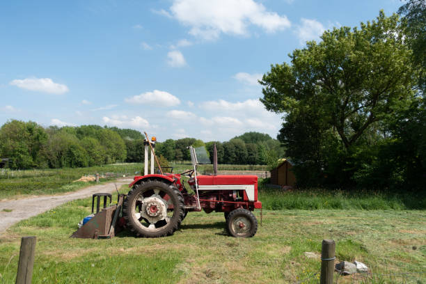 istock Vintage small red tractor on a mown meadow 958757388