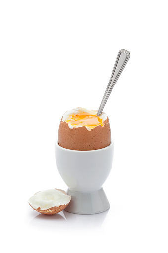 Soft-boiled egg in an eggcup isolated on white background. A spoon is in the egg. High key DSRL studio photo taken with Canon EOS 5D Mk II and Canon EF 70-200mm f/2.8L IS II USM Telephoto Zoom Lens
