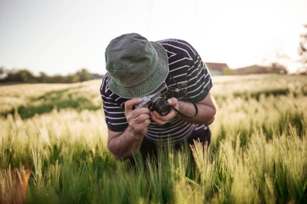istock Senior photographer taking photos on the meadow 958769954