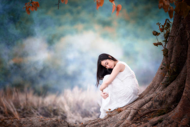 istock Young beautiful woman alone sitting under tree indian summer style 958772118