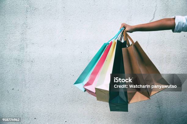 Closeup The Colorful Shopping Bags Were Holding By Lady Handin Front Of Grunge Surface Cement Wallin Abstract Art Designclassic Old Film Toneblurry Light Around Stock Photo - Download Image Now