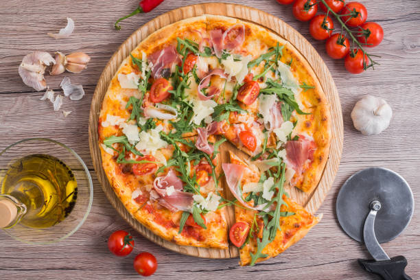 istock Fresh pizza with prosciutto meat, tomato and green arugula 958784766