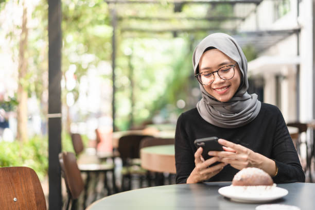 istock Young muslim woman in cafe checking her smart device. 958785076