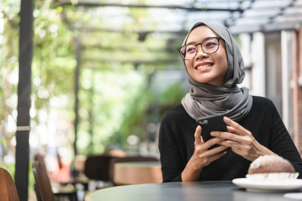 Malaysian ambitious businesswoman with smartphone in her hand. Muslim Malaysian woman during lunch break using her smartphone in Kuala Lumpur, Malaysia. indonesian ethnicity stock pictures, royalty-free photos & images