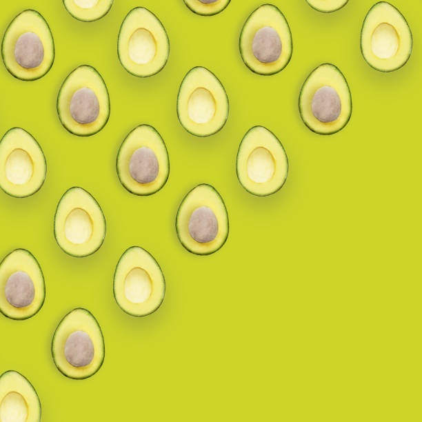 istock Avocado halves pattern isolated on green background, top view flat lay conceptual image with space for text. 958789122