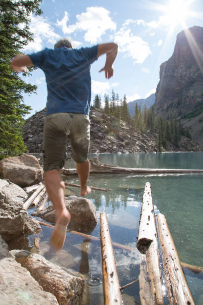 istock Male hiker jumps between logs at Moraine Lake 958800690