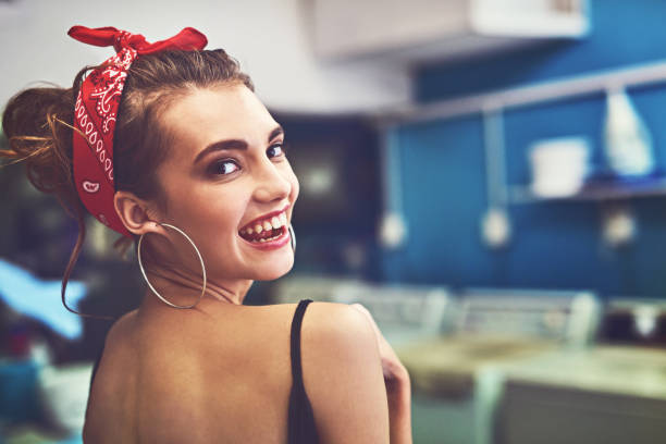 Rearview portrait of an attractive young woman standing inside of a laundry room to do washing while looking back at the camera