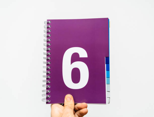 männliche hand, die notebook mit großen zahl 6 auf lila farbe - demonstrant grafiken stock-fotos und bilder