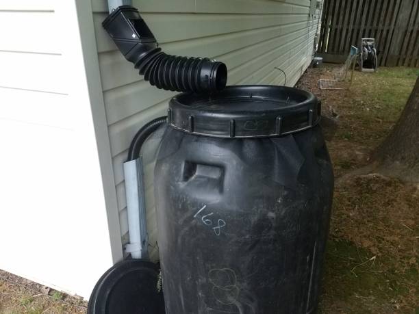 istock black plastic rain barrel installed on a house 958824804