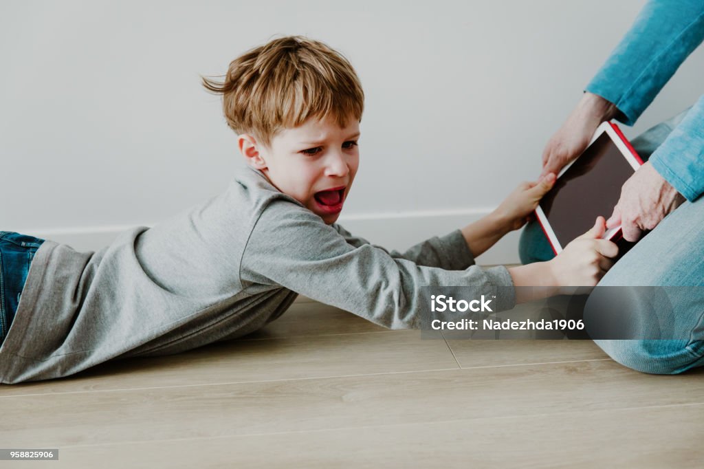 computer addiction- father taking touch pad from angry child computer addiction- father taking touch pad from angry child, technology and problems Child Stock Photo