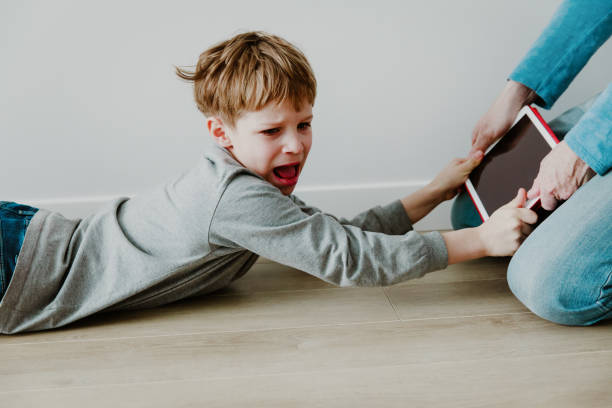 computer addiction- father taking touch pad from angry child stock photo