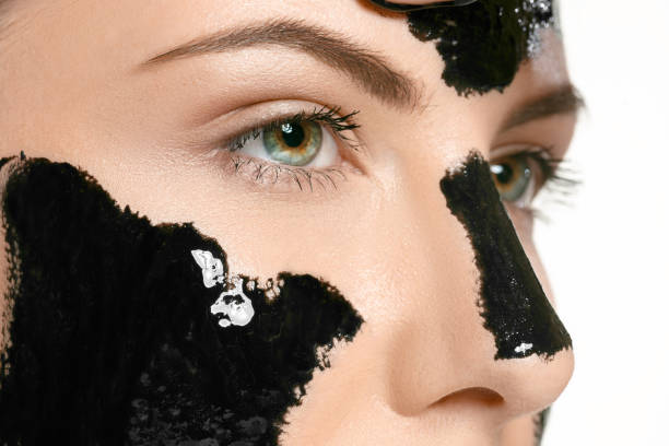 giovane bella donna che applica una maschera per il viso del fango nero terapeutico. trattamento termale - mud wellbeing spa treatment beautician foto e immagini stock