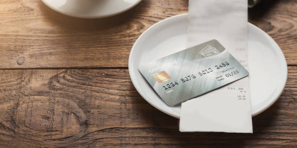 Restaurant bill and credit card on wooden table Restaurant bill for coffee and credit card on wooden table, paying for lunch at cafe, copy space restaurant table card stock pictures, royalty-free photos & images